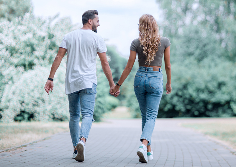 A couple holding hands walking away from the camera